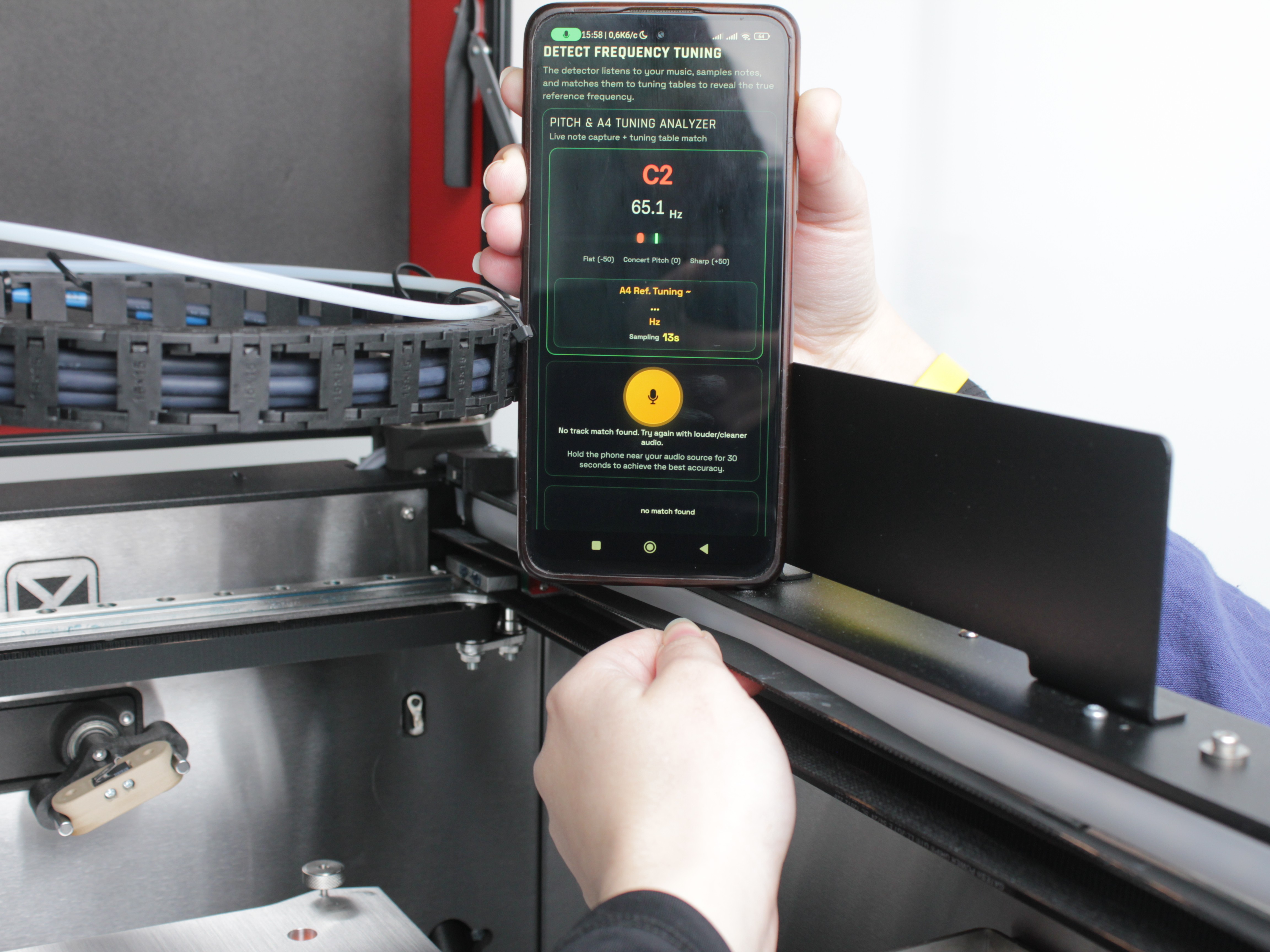 Phone with guitar tuning app next to the Y-axis belt being plucked
