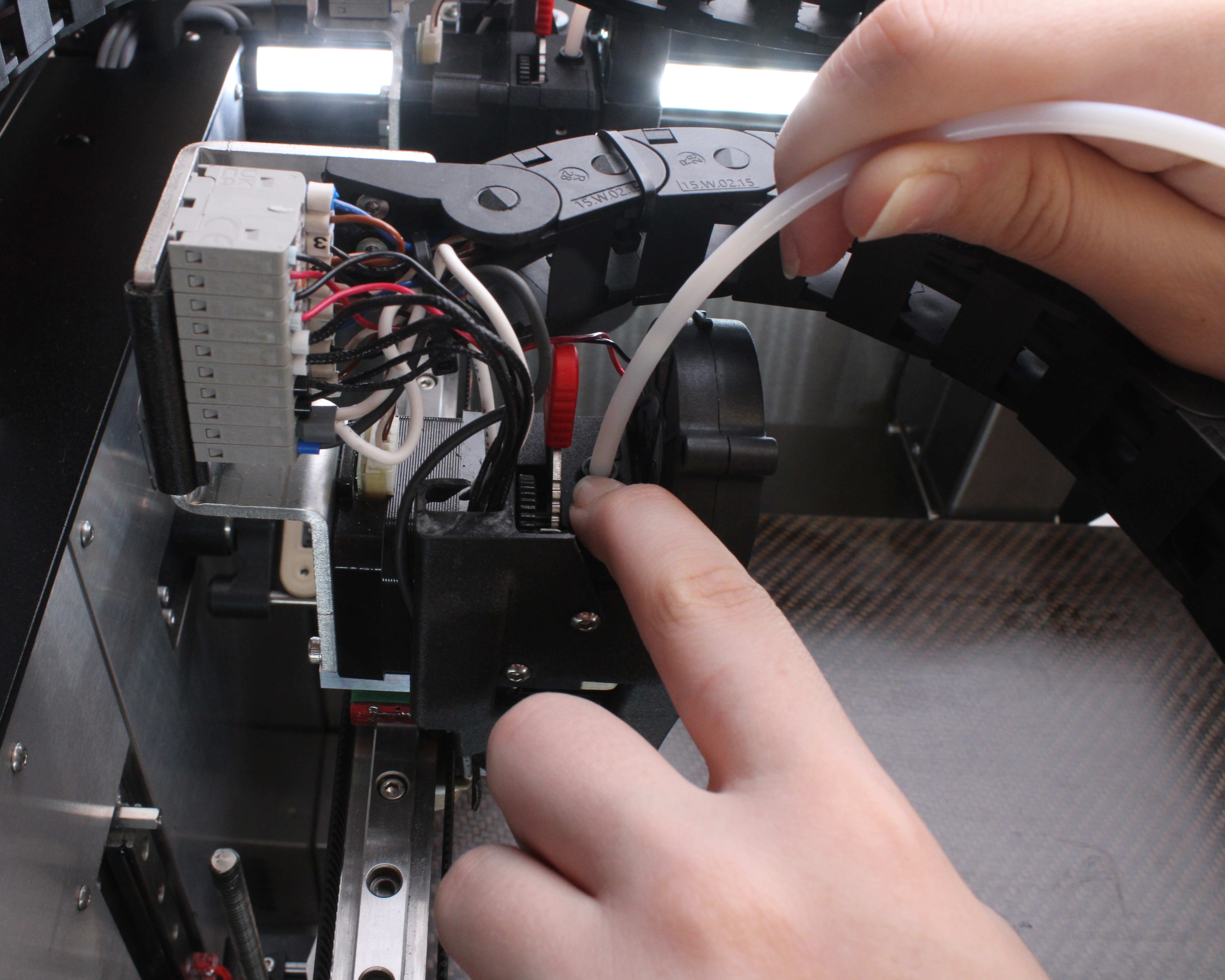 Pressing push-fit clip down while pulling tube up to disconnect from extruder.