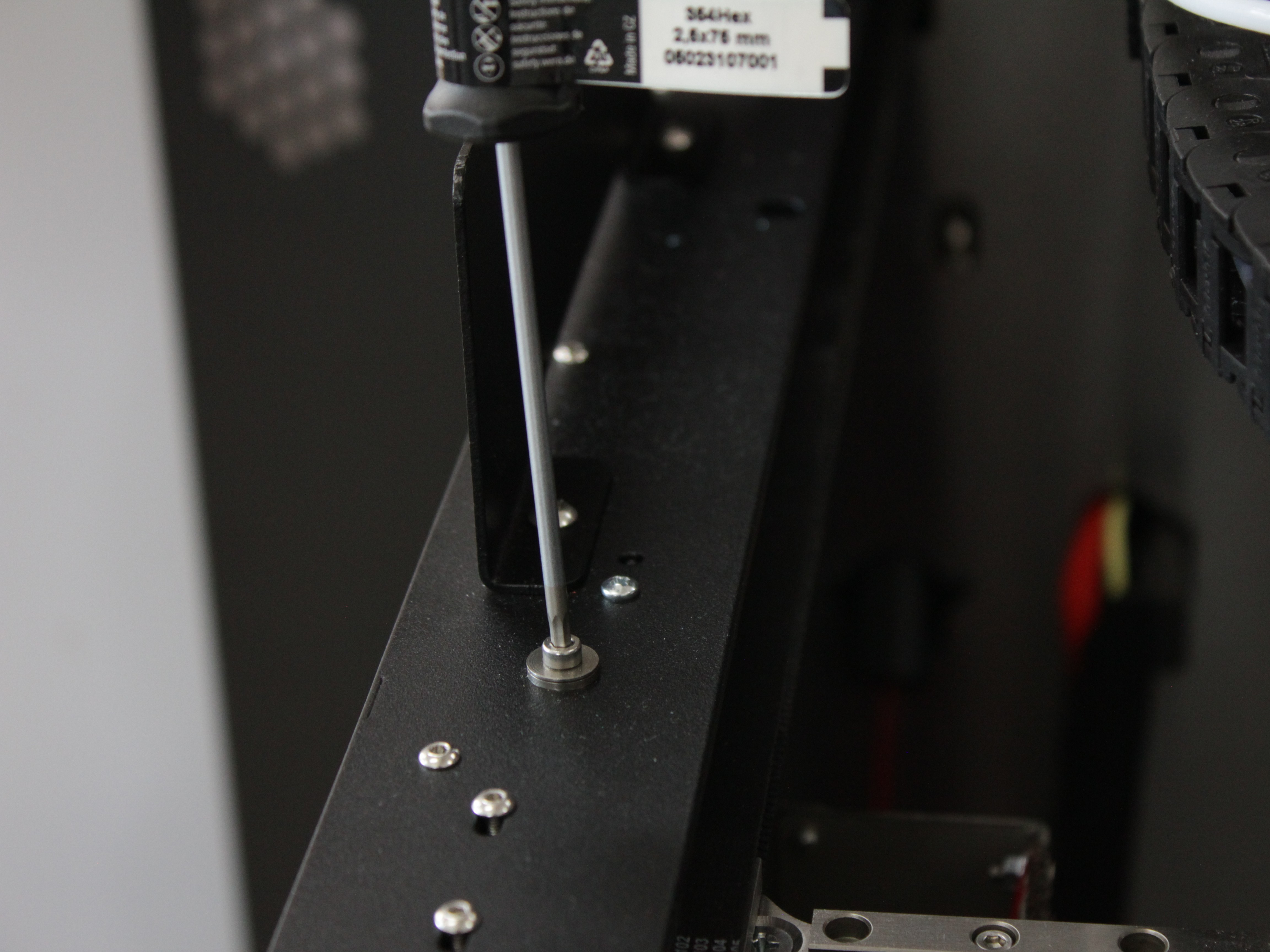 Loosening the front left Y-rail screw with hex screwdriver