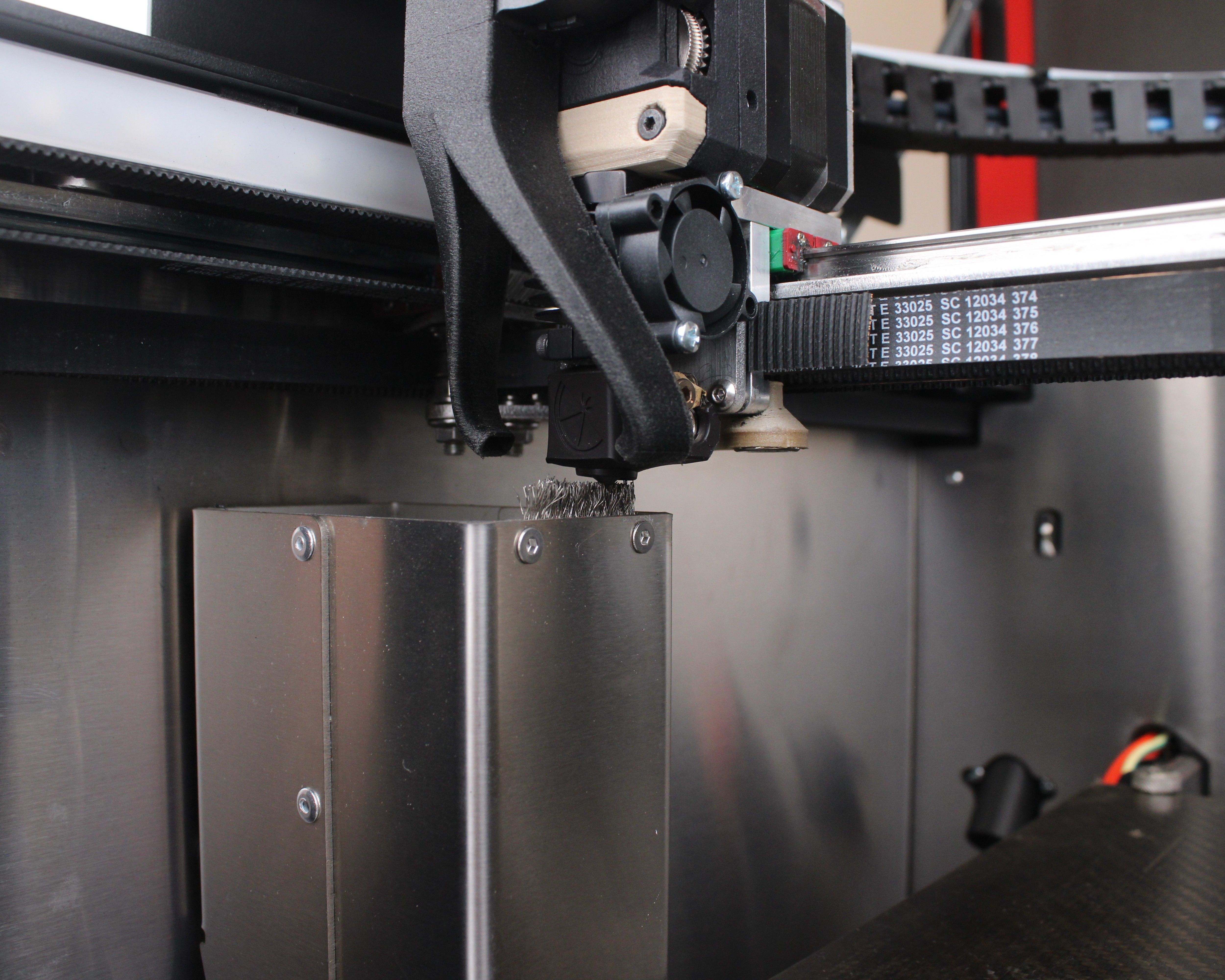 Toolhead positioned over the purge bucket with brush and nozzles visible