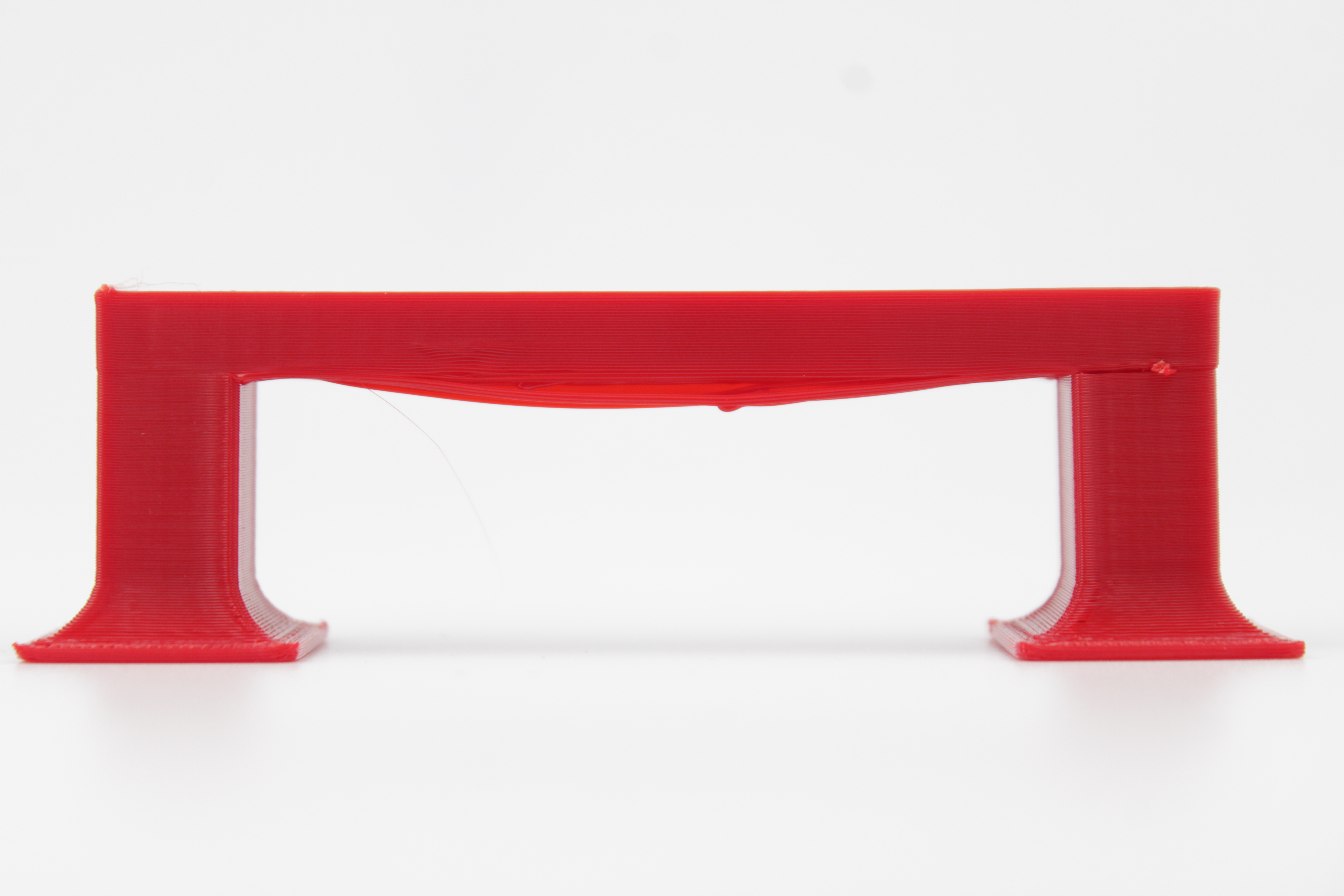 Bridging test print before tuning, with the bridge strand sagging noticeably below the span