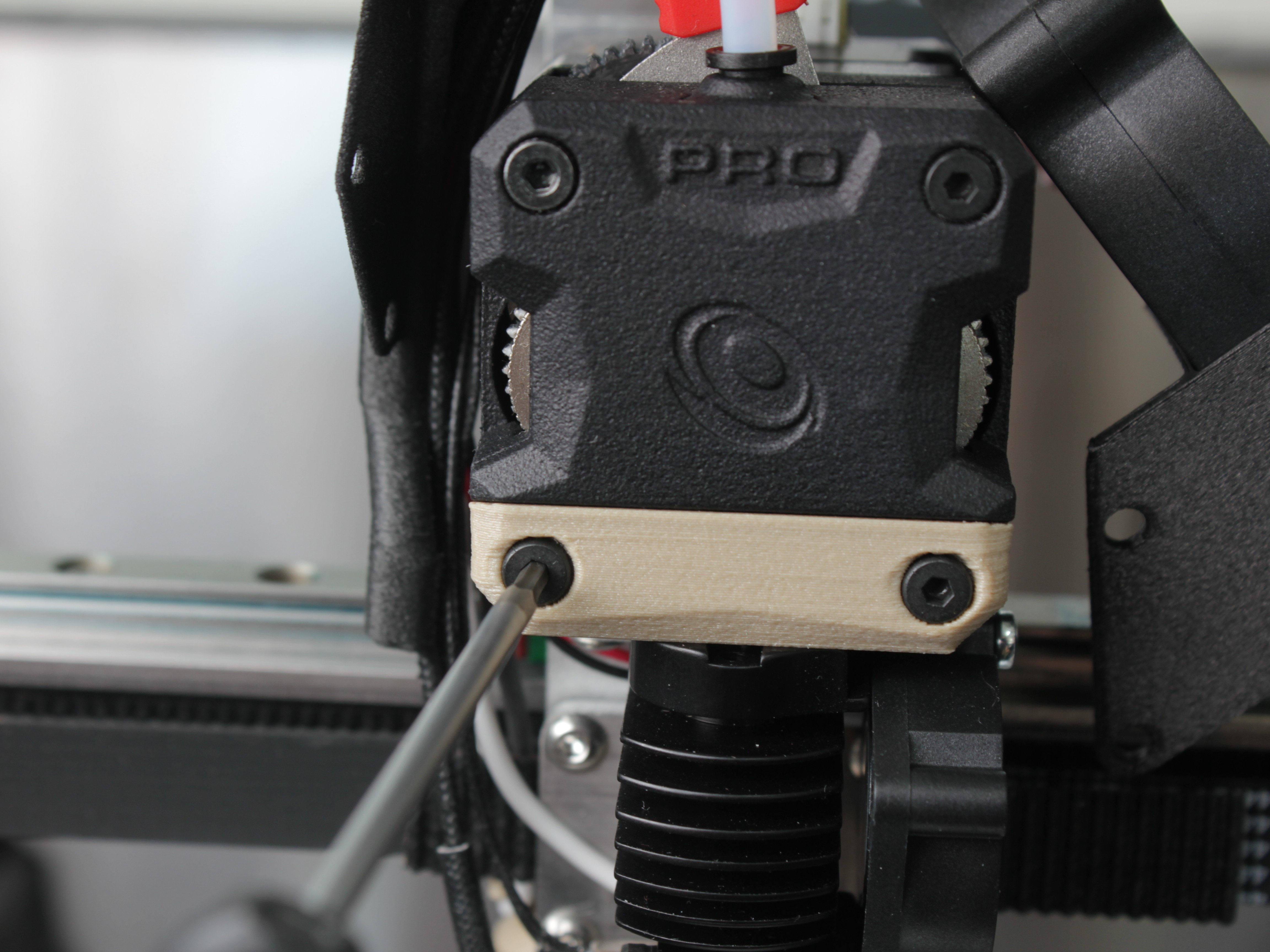Radiator adapter bracket screws being removed from extruder