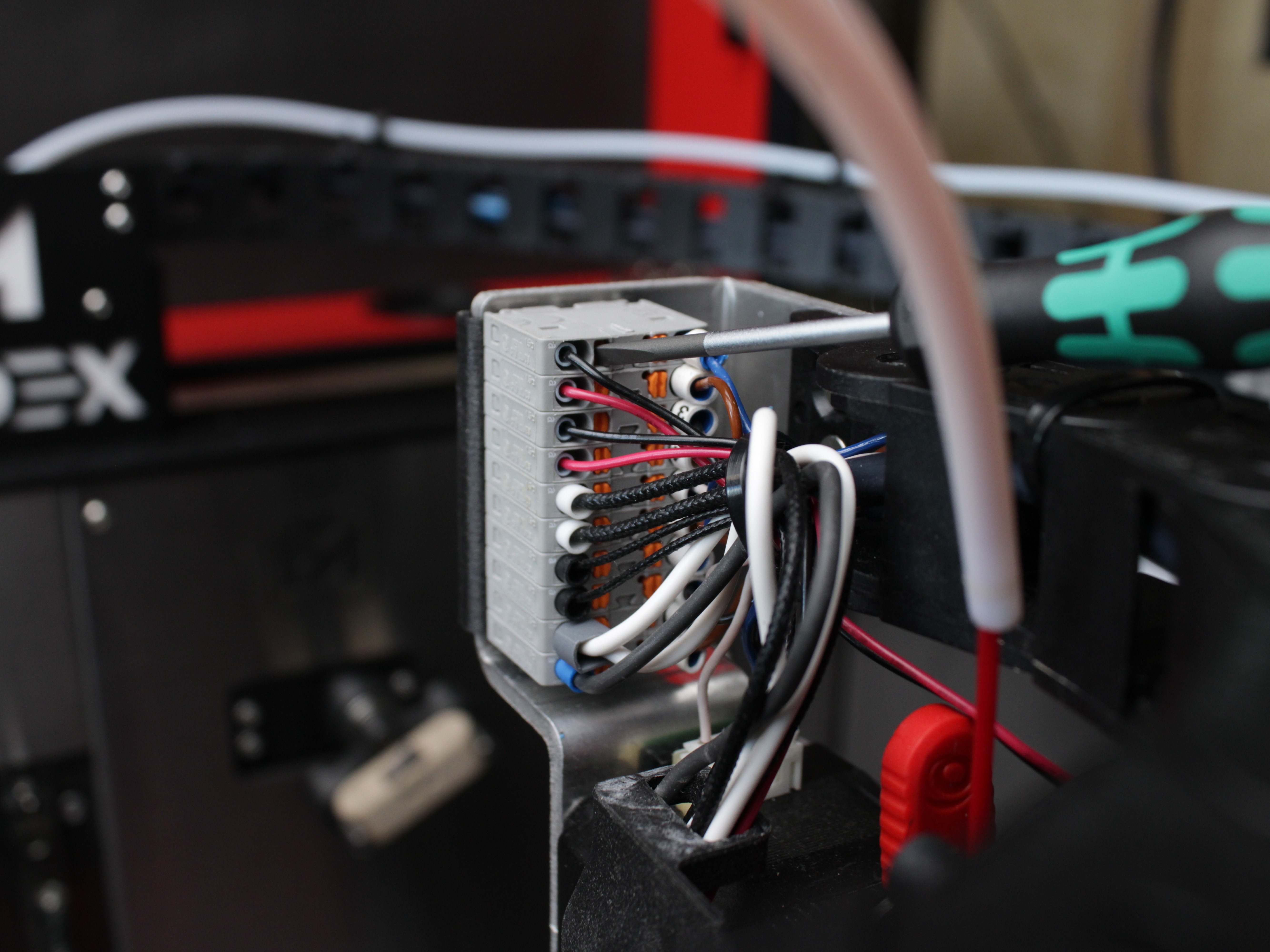 Pressing orange tab with hex driver to release wire