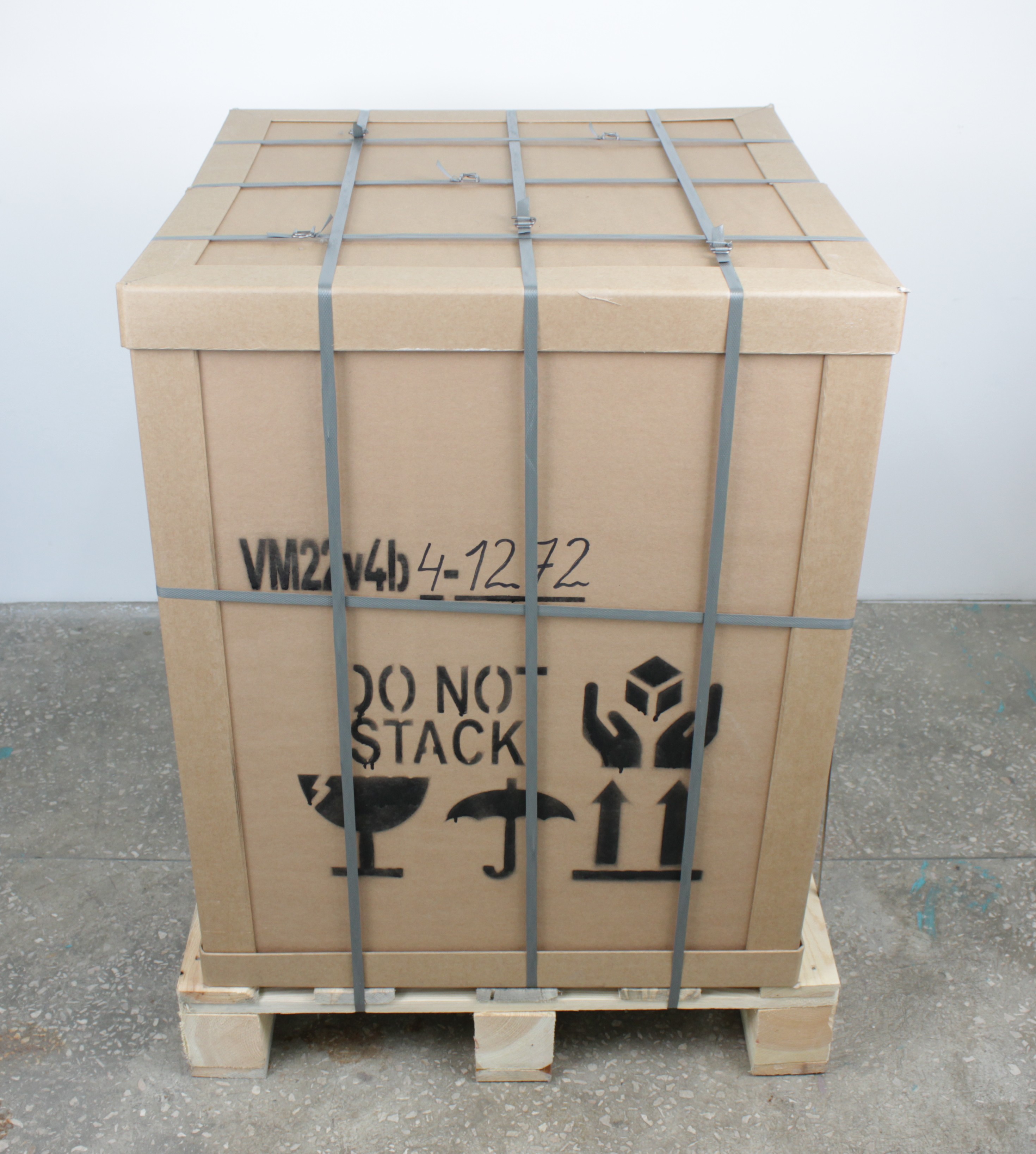 Printer secured in shipping crate on pallet with straps after removing outer wrap