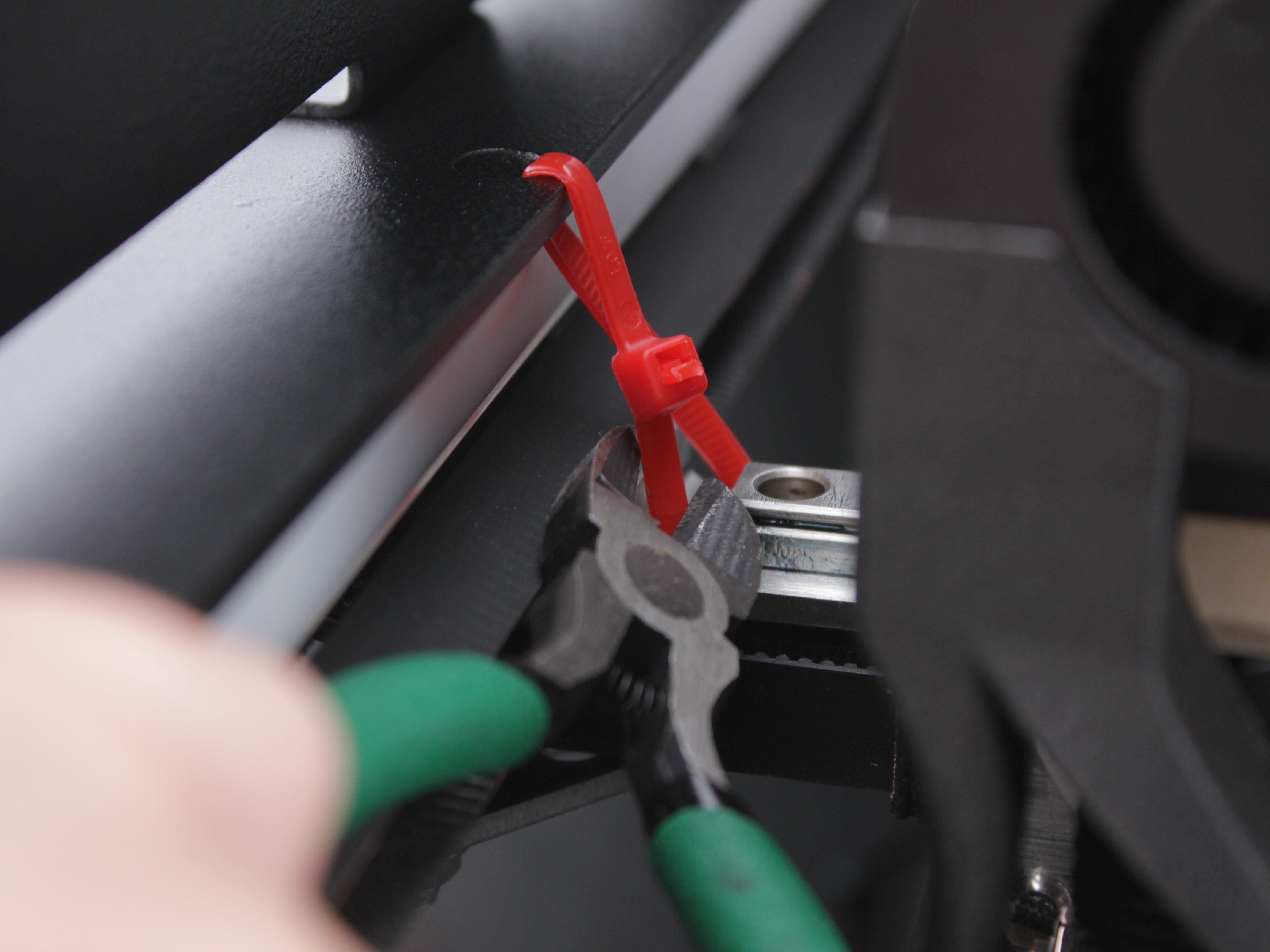 Cutting red zip tie securing left side of crossbar