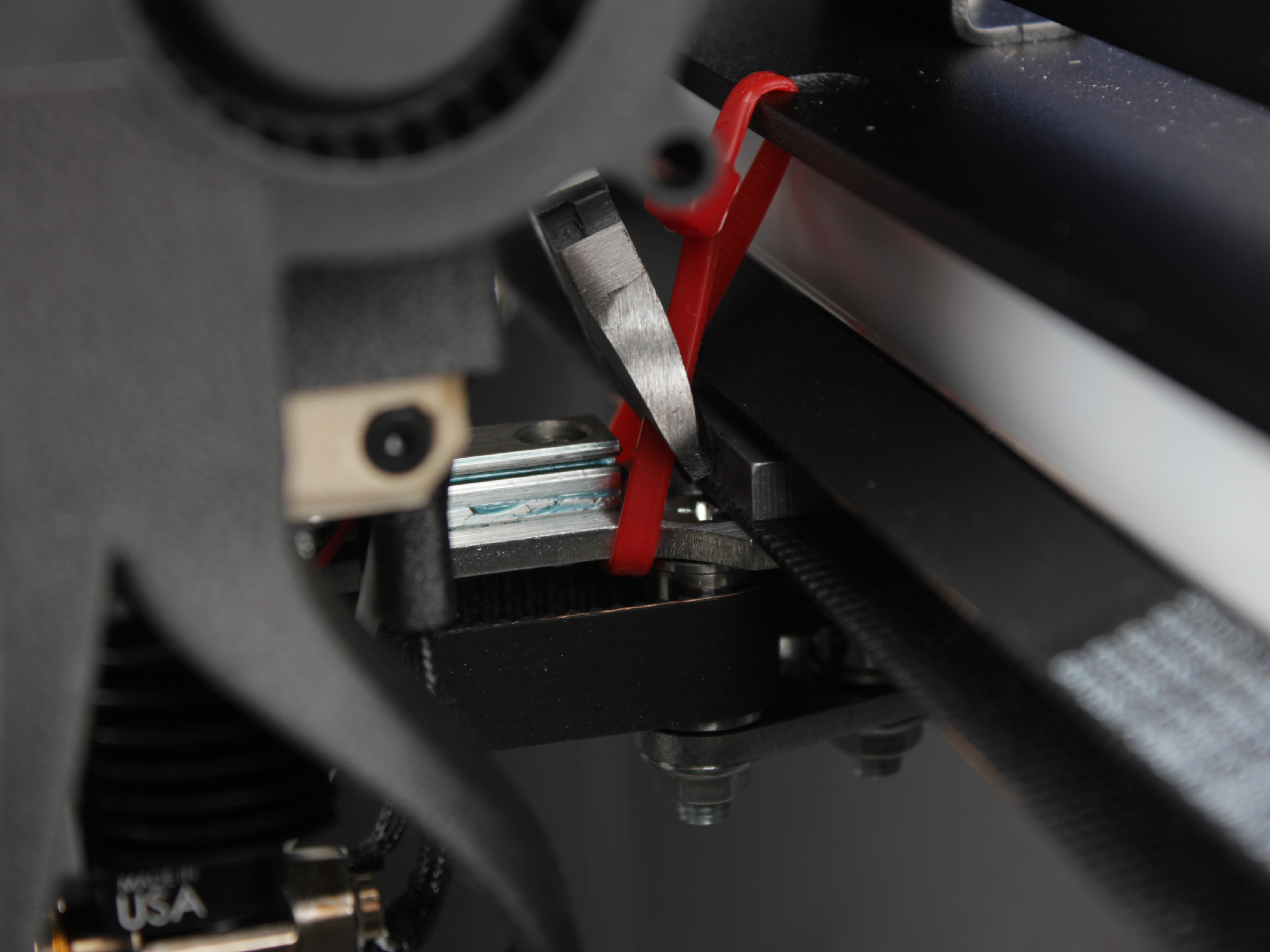 Cutting red zip tie securing right side of crossbar